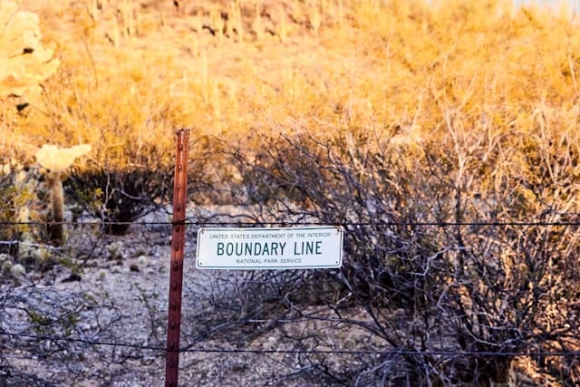 a fence with a written sign that says boundaries