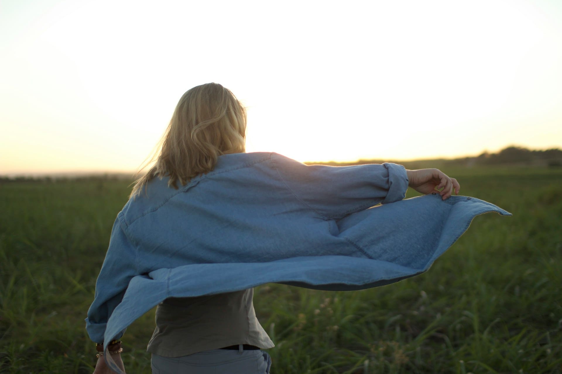 woman in nature letting wind blow up her vest