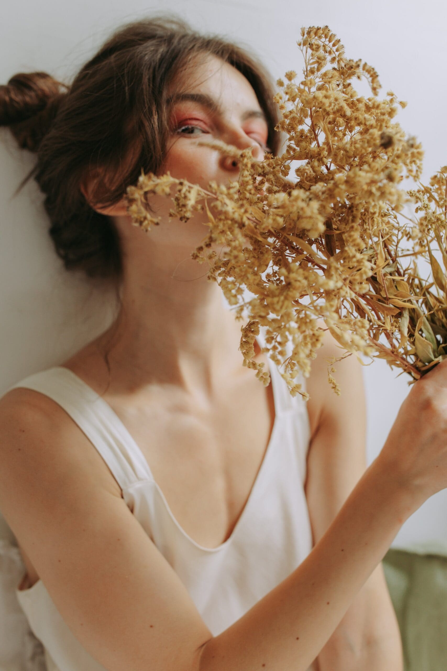 Woman gently holding flowers with here eyes closed