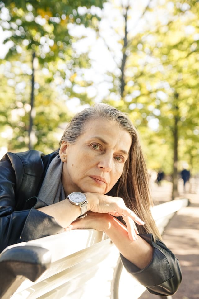 a woman sitting outdoors with a thoughtful expression, resting her chin on her hands — inner critic examples