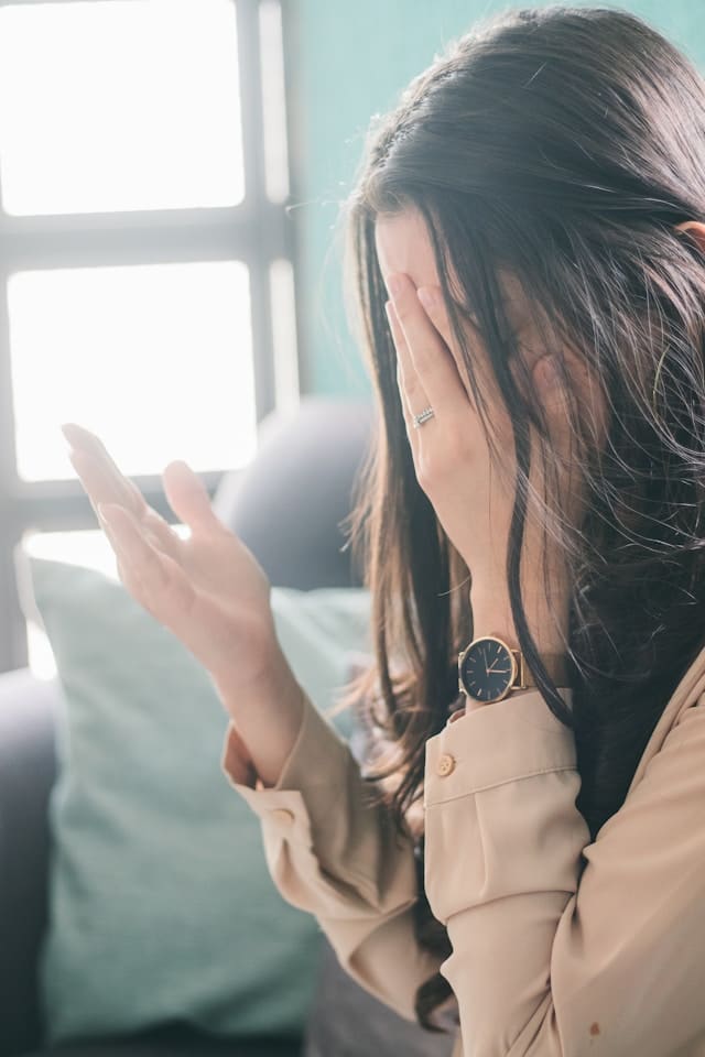 why do I always apologize — a woman covering her face, turned inward, one hand raised