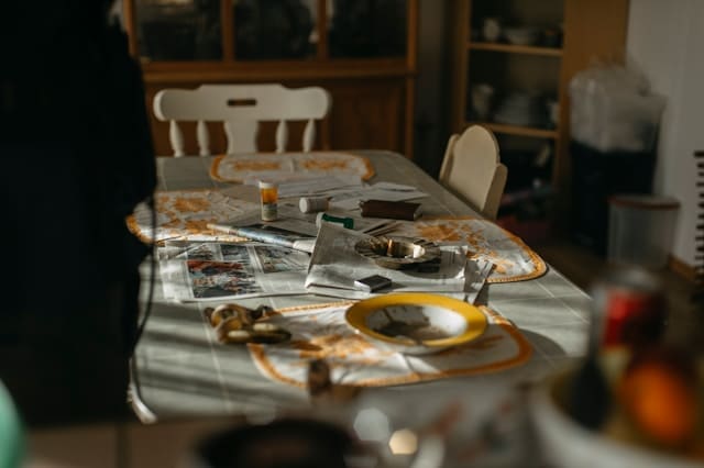 A lived-in kitchen table in morning light, scattered with the traces of a busy household.